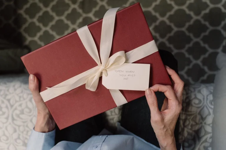 Close-up of a woman receiving a gift box with a white ribbon, evoking warmth and thoughtfulness.