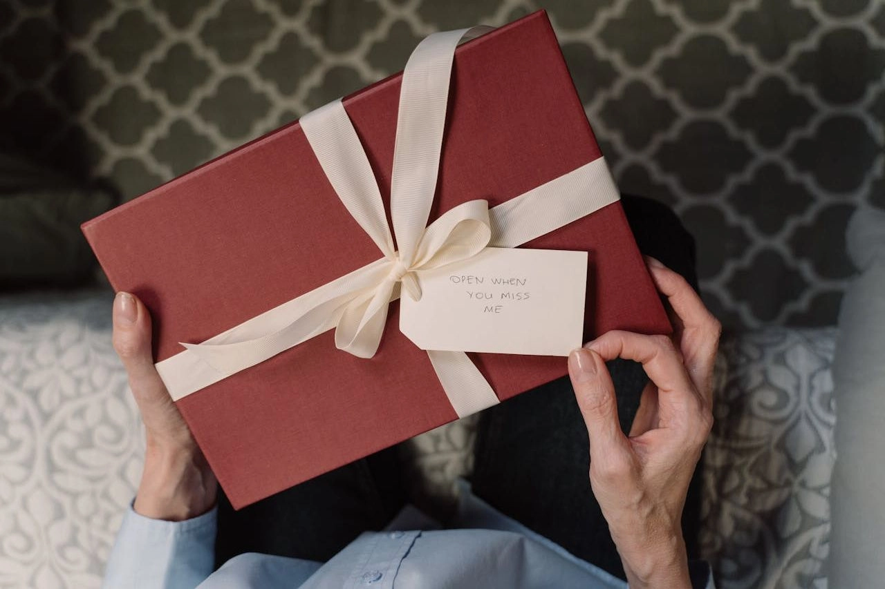 Close-up of a woman receiving a gift box with a white ribbon, evoking warmth and thoughtfulness.